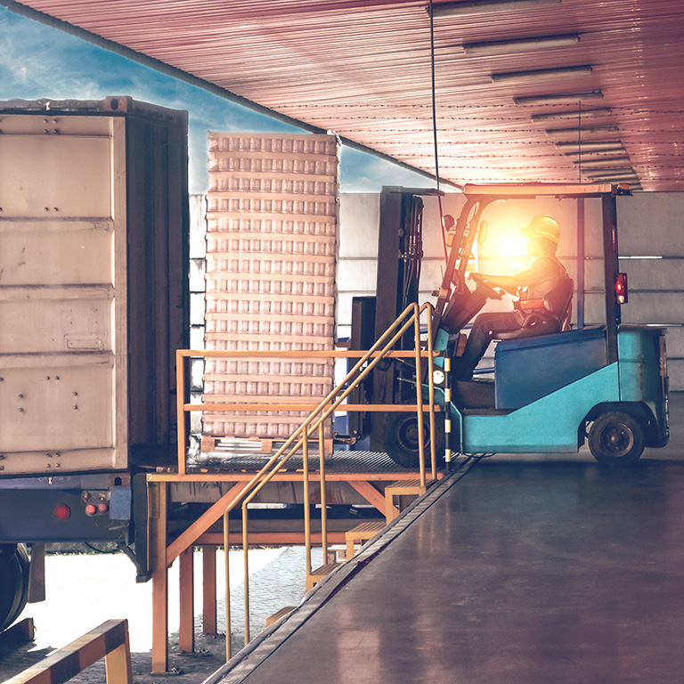 Forklift moving shipment from container into warehouse